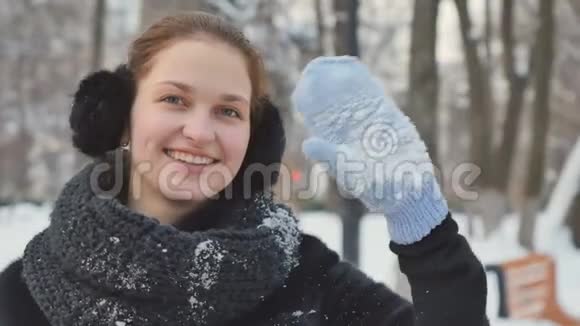 在冬季公园的背景下漂亮的女士用手套挥动双手对着镜头视频的预览图