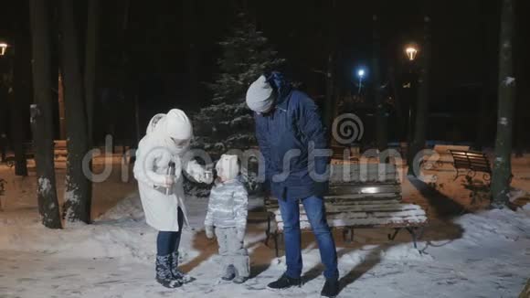 一个年轻的家庭在傍晚的冬季公园里喝茶取暖视频的预览图