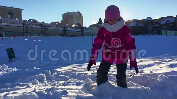 孩子玩冬天有趣的游戏在阳光下玩雪的女孩视频的预览图