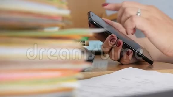 女性手在桌面上使用智能手机上面有文件和文件视频的预览图
