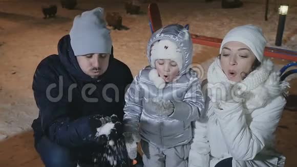 年轻的一家人慢慢地在手套上吹雪视频的预览图