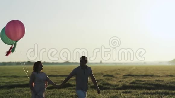 一对夫妇在田野里散步在日落时牵手拍得很慢视频的预览图