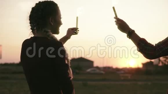 在日落的时候微笑的朋友在用烟火蜡烛挥手时玩得开心镜头耀斑慢镜头视频的预览图