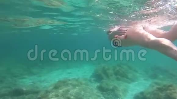一位身穿黑色比基尼的年轻美女带着面具和浮潜在蓝色的水里游泳动作缓慢视频的预览图