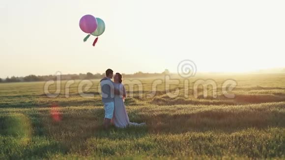 可爱的情侣站在田野里手里拿着氦色的球视频的预览图