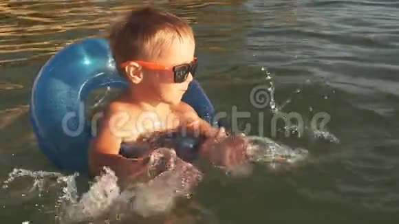 快乐的小男孩在水里溅起水花日落时在海上玩的孩子视频的预览图