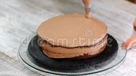 特写饼干奶油以螺旋的形式出现在蛋糕上巧克力海绵蛋糕加奶油准备蛋糕视频的预览图