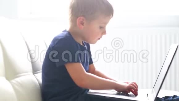 快乐男孩玩电脑的肖像有魅力的孩子家里有笔记本电脑娱乐技术未来主义视频的预览图