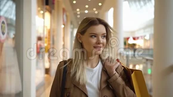 快乐的金发女郎微笑着带着购物袋在购物中心走来走去视频的预览图