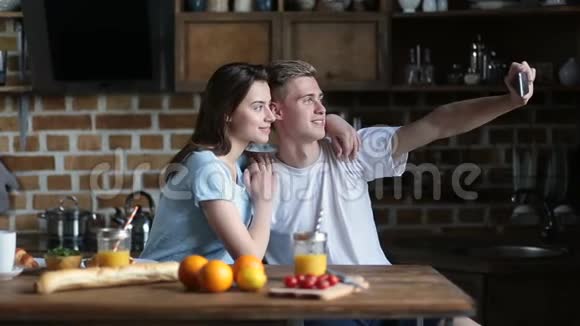 一对快乐的情侣在厨房里用手机自拍视频的预览图