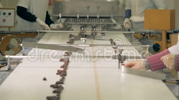三名工厂工人在传送带上挑选和分类巧克力糖果视频的预览图