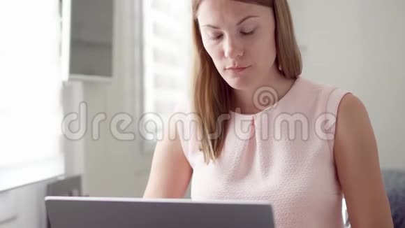 年轻漂亮的职业女性在家里用笔记本电脑工作远程自由工作视频的预览图