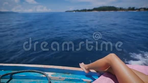 一位年轻女子在海上游轮上躺在公海帆船甲板上的腿部形象赤裸的双脚视频的预览图