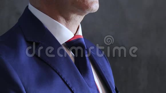 男人手臂调整蓝色领带在喉咙靠灰色的墙壁侧视视频的预览图