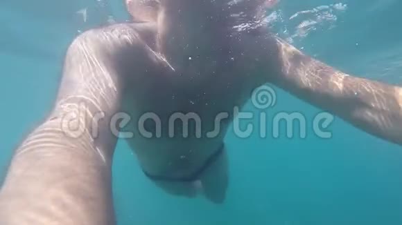 无法辨认的人拿着相机在海里游泳在水下封闭男性身体慢动作视频的预览图
