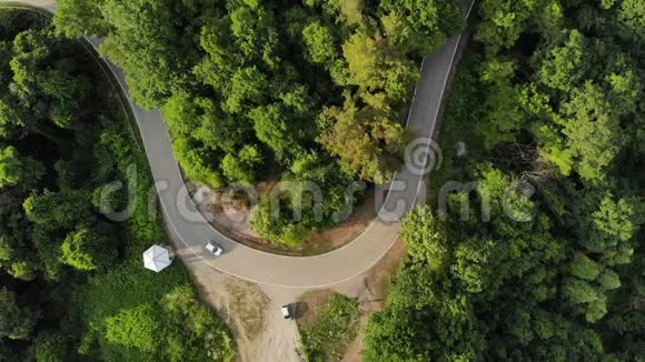林中乡村公路上白色汽车行驶的鸟瞰图无人驾驶飞机射击飞行视频的预览图