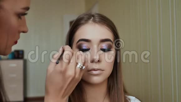 女性化妆着色的人造睫毛女孩化妆艺术家与模特合作视频的预览图