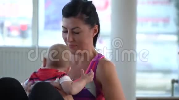 一位穿着运动服的妇女坐腹部与带孩子的母亲一起训练视频的预览图