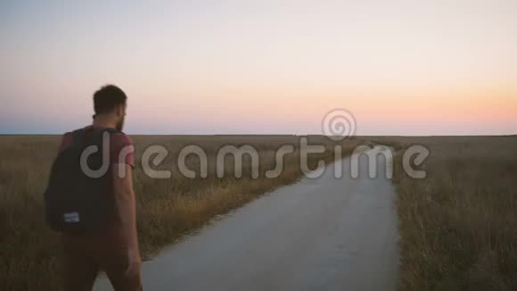 一个背着背包的人在日落时分走上去野外的路用手机说话背面视频的预览图