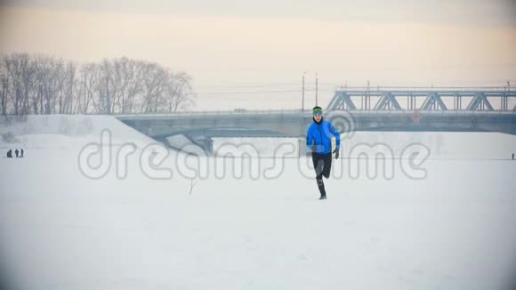 年轻的男运动员在冬天跑得很快穿过雪冰场视频的预览图