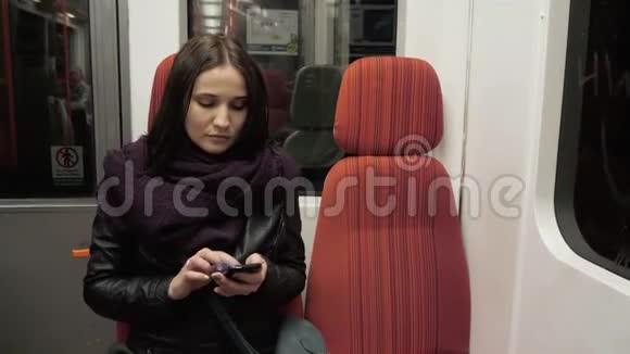 地铁列车上年轻女性手机打字信息的画像智能手机的布鲁内特女士视频的预览图