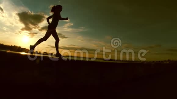 日落时分在公园里奔跑的年轻女子慢动作剪影视频的预览图