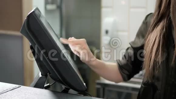 服务员在收银台附近的一家餐厅使用触摸屏关闭女服务员手查订单视频的预览图