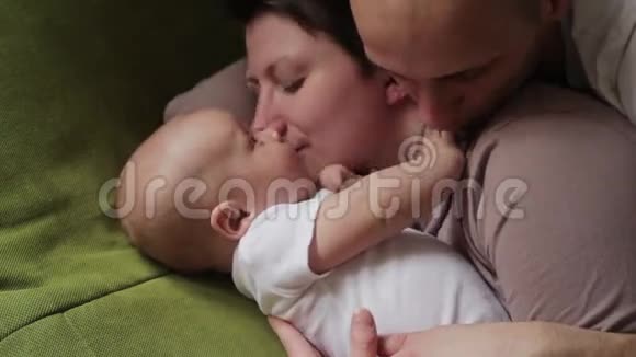 爸爸妈妈和他的小儿子在床上玩幸福家庭概念视频的预览图