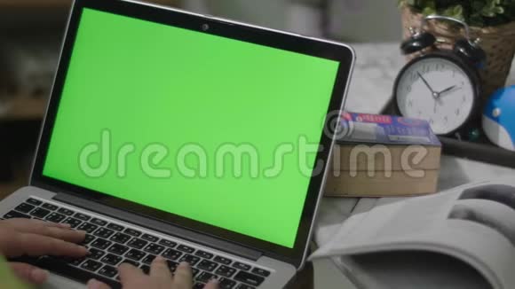 女人在家里用绿色屏幕在笔记本电脑上工作铬钥匙从后面看视频的预览图