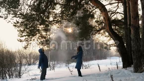 男人和女人在冬天的森林里打雪球冬天森林里的日落视频的预览图