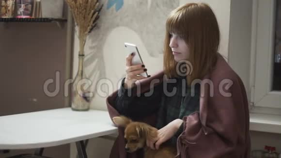 年轻漂亮的红发女人晚上在厨房用智能手机视频的预览图