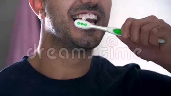 一个年轻人在浴室刷牙的反映一个男人在公寓里刷牙的特写镜头视频的预览图