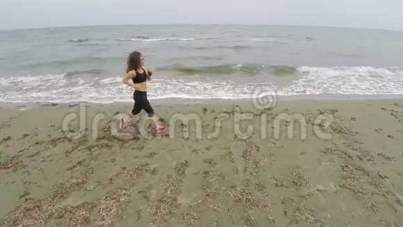 美丽的女人在海滩上奔跑从空中俯瞰女运动员运动视频的预览图