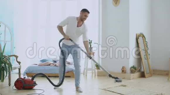 年轻男子用吸尘器打扫房子像女人一样跳舞视频的预览图