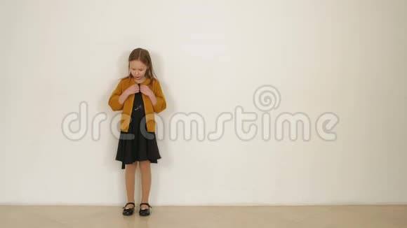 白色墙壁背景上戴着黑色闪亮帽子和连衣裙的小女孩的肖像视频的预览图