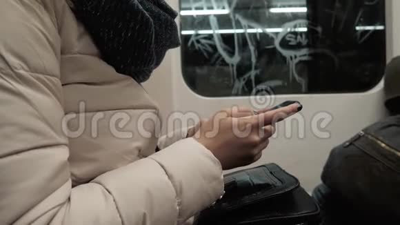 地铁列车上年轻女性手机打字信息的画像金发女性智能手机视频的预览图