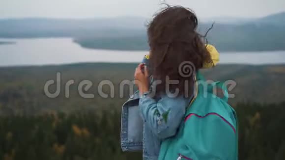 美丽的女人站在山顶上长长的头发随风飘扬微笑着试图保住她的头发视频的预览图