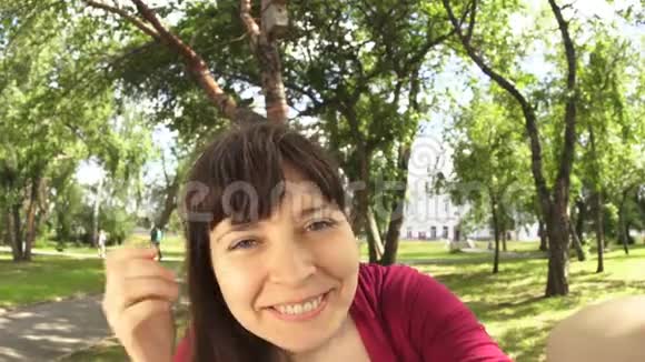 年轻快乐的女人在公园的长凳上自拍时挥动着她的手视频的预览图
