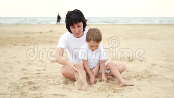 快乐的妈妈和她的孩子在海边玩沙子动作很慢视频的预览图