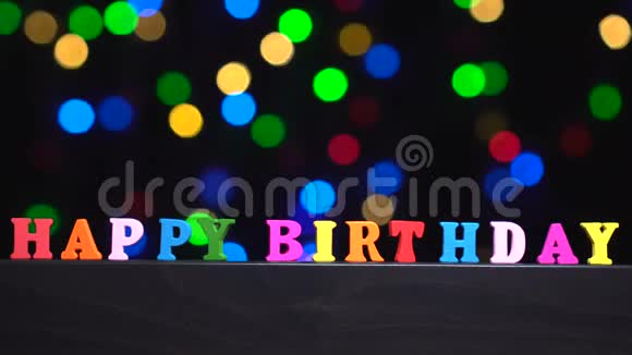 五颜六色的字生日快乐由多种颜色的木制字母在抽象模糊的灯光前背景视频的预览图