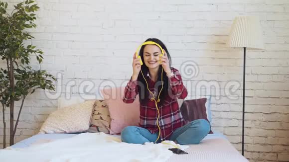 混合种族妇女在床上听耳机音乐视频的预览图