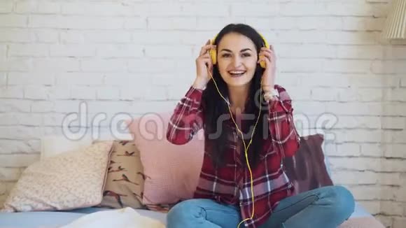 女孩带着耳机听音乐坐在床上跳舞视频的预览图