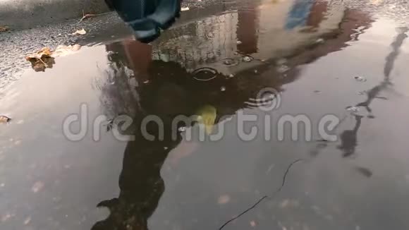 黑色运动鞋中男腿的慢动作特写镜头带着倒影踏入泥泞的水坑视频的预览图