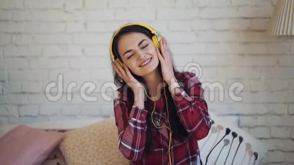 女孩带着耳机听音乐坐在床上跳舞视频的预览图