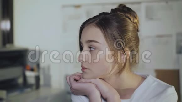可爱的女孩坐在工作场所靠在手上对着镜头微笑视频的预览图