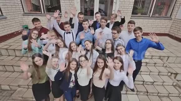 一大群快乐的学生在学校的台阶上挥手视频的预览图