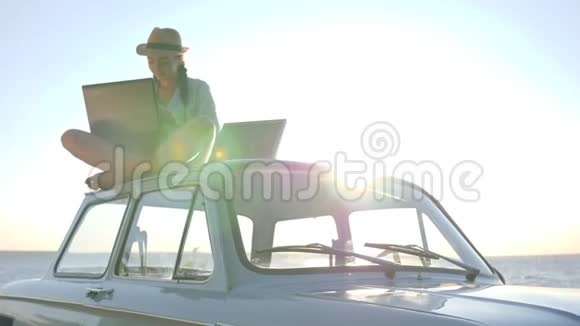 可再生能源女性坐在经典的老式汽车上笔记本和电池在背景天空阳光下视频的预览图