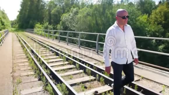 一个秃顶的人在一座废弃的铁路桥上唱歌中弹视频的预览图