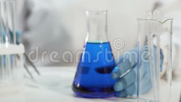实验室助理将干冰放入锥形瓶中的蓝色液体中煮沸视频的预览图