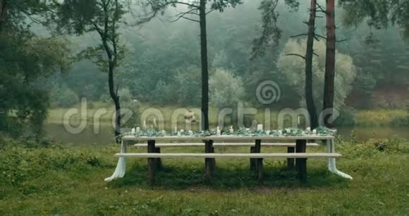 将相机移向餐桌用树叶鲜花双层蛋糕和蜡烛装饰视频的预览图